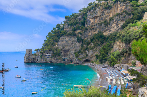 Fototapeta Naklejka Na Ścianę i Meble -  The most beautiful beach in Positano in Italy: view of Fornillo beach, composed of sand mixed with pebbles and light gravel with a watchtower set on a black cliff.