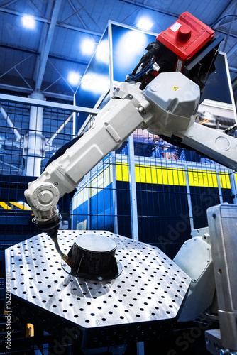 Industrial robot arm welding metal part in factory. Automation and manufacturing technology concept.