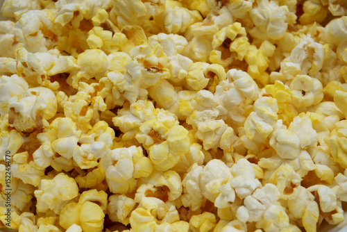 Close-up of freshly popped buttered popcorn. A golden, crispy, and tasty snack ideal for movie nights or food-related content. High-resolution macro image with vibrant yellow and white tones. 