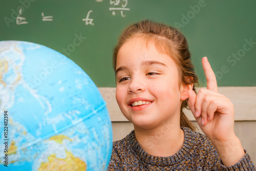 Girl with globe during geography lesson at school