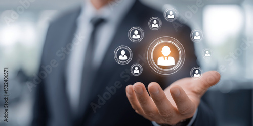 Businessman presenting virtual human resource network, digital recruitment and talent management concept with icons floating above his hand in modern office background. Selective focus.