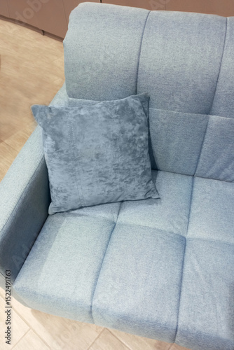 Light blue sofa with armrest and decorative pillow in the room.