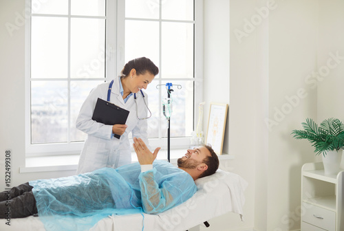 Papier peint Female doctor talks with man patient, happy to announce good results after curing disease, consulting and giving recommendations, posing in clinic
