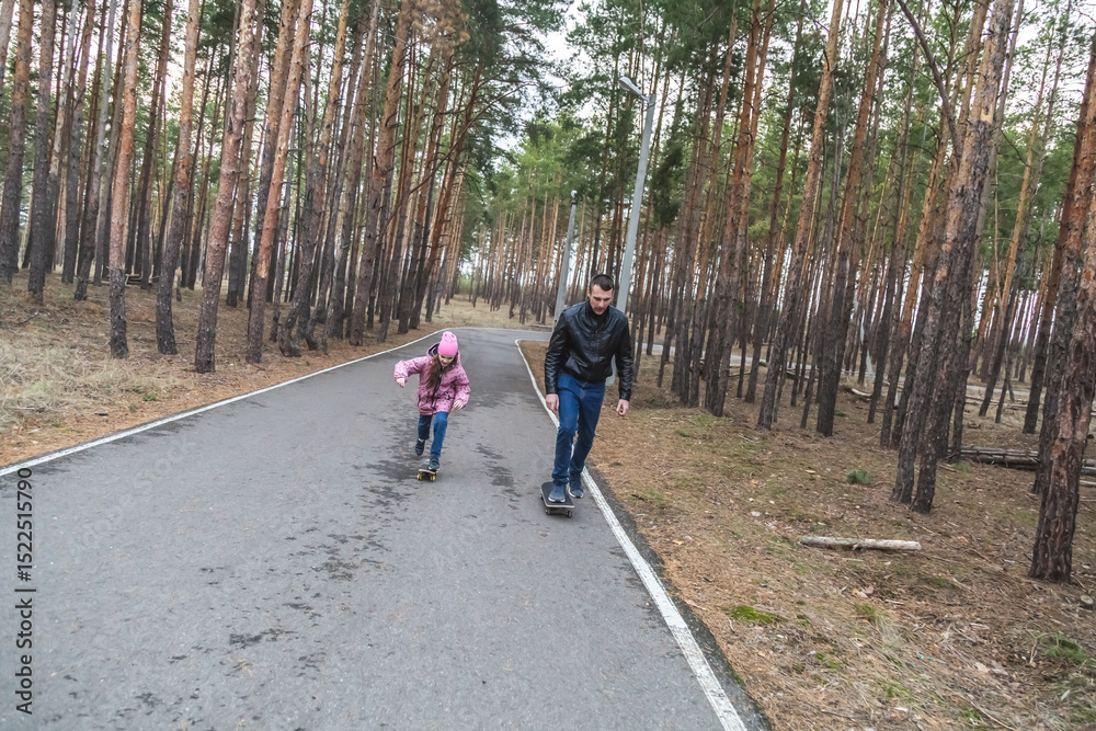 Obraz premium Father and daughter riding skateboards in the forest.