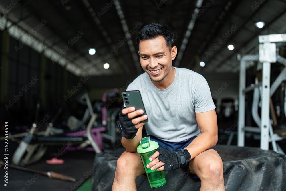 Post-Workout Relaxation. Smiling man checking phone after gym workout, feeling accomplished. Post-Workout Relaxation. Smiling man checking phone after gym workout, feeling accomplished.