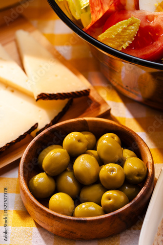 Cheese and salad dish with green olives in wooden bowl