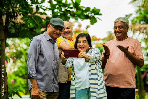 Photography Checking photos on smartphone, elderly Indian group smiles while standing in lus