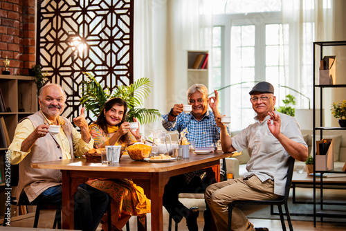 Seniors serving and eating together during happy indoor reunion around modern Indian dining table