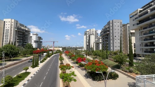 Tel Aviv. Israe Cozy modern residential area, highway, cars, flowering Flamboyant trees. Road without traffic jams