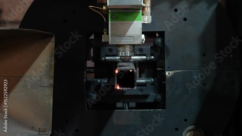 Laser cutting machine processing square metal tube in factory with 360-degree rotation. Front view