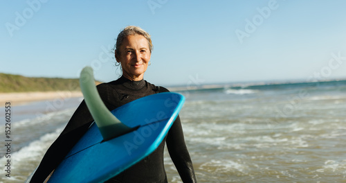 Photography Mature woman posing with a single fin surfboard at the beach