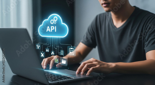 Hands typing on laptop with digital cloud labeled API and interconnected technology icons illustrating cloud computing and software integration concepts in a modern workspace photo