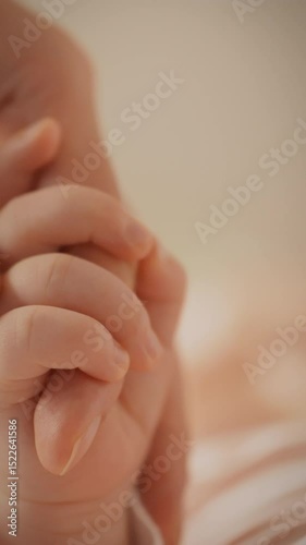 A mother tenderly touches her newborn's hand as the child confidently grasps onto her finger, showcasing a deep bond. This intimate moment captures love and warmth in a cozy setting