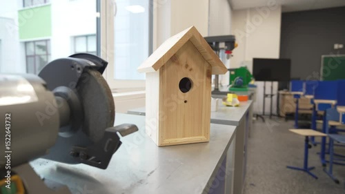Handcrafted wooden birdhouse created by students rests on classroom windowsill. Simple design reflect fine beginner woodworking skills