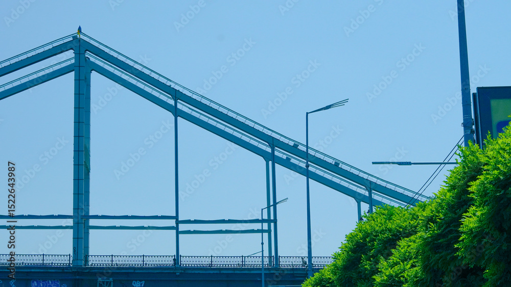 Fototapeta premium Minimalist pedestrian bridge underframe photographed from below in urban setting.