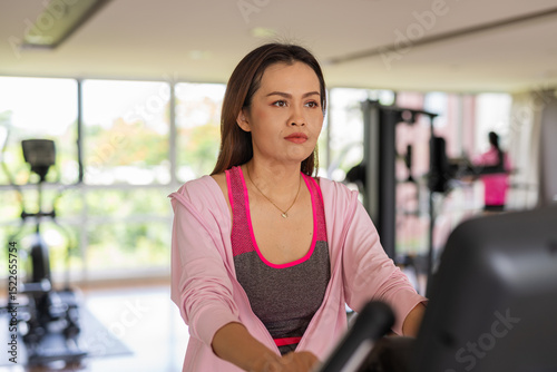 Happy woman at the gym exercising and having healthy workout indoors with exercise bike Free Download Happy woman at the gym exercising and having healthy workout indoors with exercise bike - GFXLoad