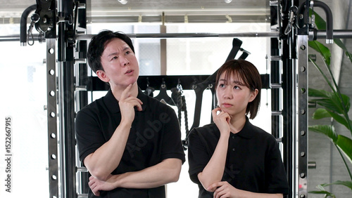 Tableau sur toile Asian Male and Female Gym Staff Sharing Concerns in a Fitness Center