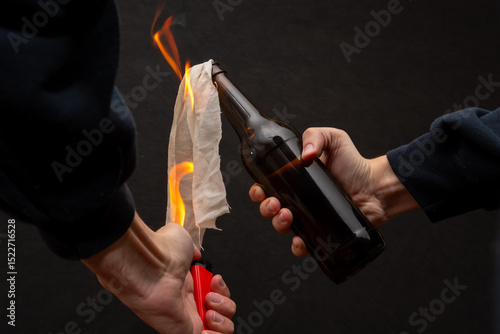 A man lights a cloth in a bottle, igniting a molotov cocktail.