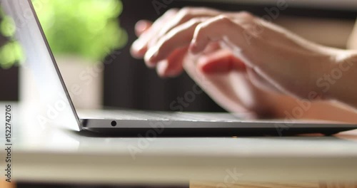 Hand of woman using laptop computer to work, typing at home and scrolling, while sitting on table workplace at night, Close-up of young women hand	
