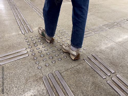 Close up view of person walking on tactile paving tiles for visually impaired people in a metro or public space. Accessibility and mobility support in urban pedestrian design