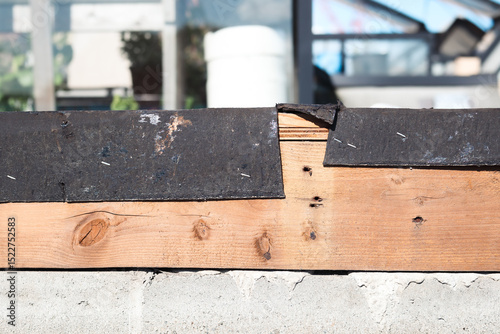 Roof metal flashing removed or blown off. Waterproofing flat roof or roof repair. Modified bitumen roofing membrane and wood section. Base sheet not covering to parapet wall topside. Selective focus.