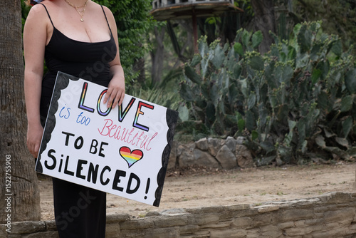 Woman holding love is too beautiful to be silenced sign at pride parade