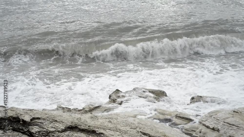 Detailed stormy big wave splash. Waves wash over white rocks on the shore. Waves crashing over rocks.