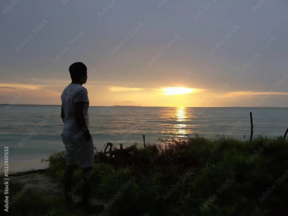 Fototapeta premium silhouette of a man standing on the beach at sunset