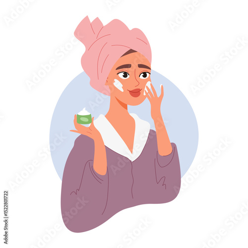 Woman with towel on head applies cream to her face. Beauty treatment and self-care concept