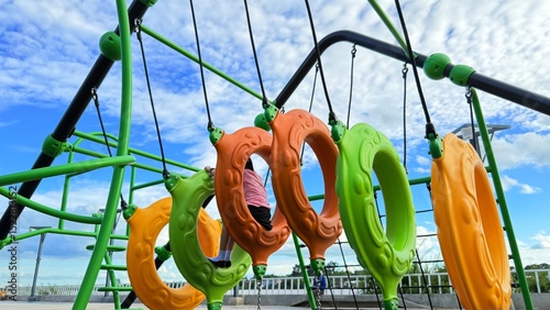 Kid, hanging and monkey bars play outdoors playground, climbing or games with exercise of motor development. Outdoors, development and portrait of kids for playing, freedom and summer adventure with s