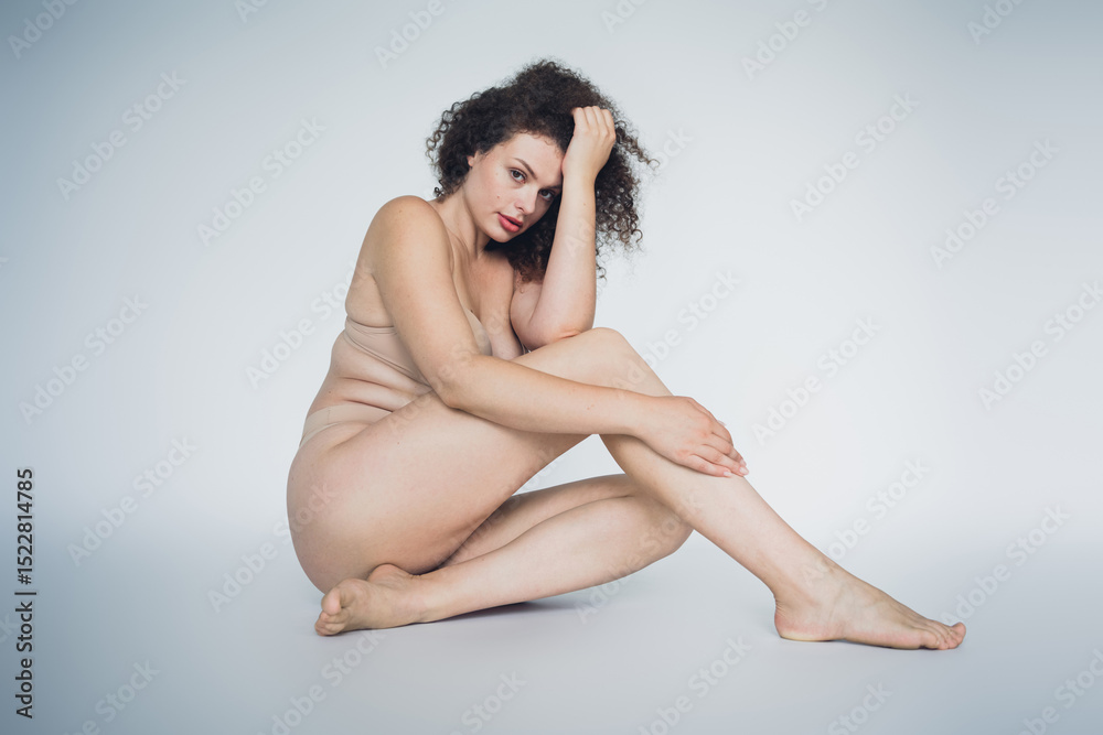 Obraz premium Sensual Woman Embracing Body Positivity with Natural Beauty and Lingerie on a White Background in Grey Toned Studio