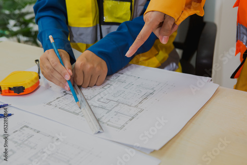 An Asian female engineer reviews and discusses detailed house construction plans  structural integrity, design accuracy, and successful project execution.