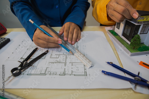 An Asian female engineer reviews and discusses detailed house construction plans  structural integrity, design accuracy, and successful project execution.