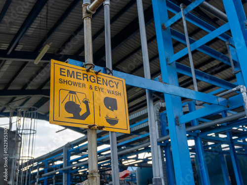 Yellow emergency shower and eye wash sign in the chemical industry area. Wash the part that is exposed to the chemical