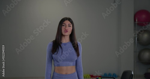 A sporty girl announcer engages viewers with fitness tips in a bright gym. She speaks directly into the camera showcasing her passion for health and exercise during a lively workout session.