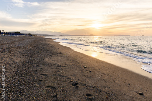 Fototapeta Naklejka Na Ścianę i Meble -  Beautiful coastline with a sandy and pebble beach at sunset. Beautiful sky coloration in the tourist and hotel area of ​​Platanes Beach, Rethymno, Crete, Greece