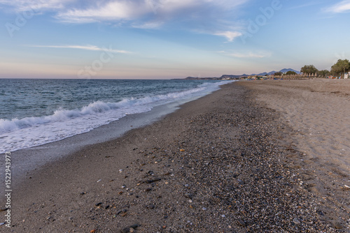 Fototapeta Naklejka Na Ścianę i Meble -  Beautiful coastline with a sandy and pebble beach at sunset. Beautiful sky coloration in the tourist and hotel area of ​​Platanes Beach, Rethymno, Crete, Greece