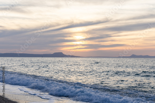 Fototapeta Naklejka Na Ścianę i Meble -  Beautiful coastline with a sandy and pebble beach at sunset. Beautiful sky coloration in the tourist and hotel area of ​​Platanes Beach, Rethymno, Crete, Greece