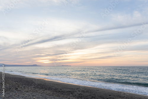 Fototapeta Naklejka Na Ścianę i Meble -  Beautiful coastline with a sandy and pebble beach at sunset. Beautiful sky coloration in the tourist and hotel area of ​​Platanes Beach, Rethymno, Crete, Greece
