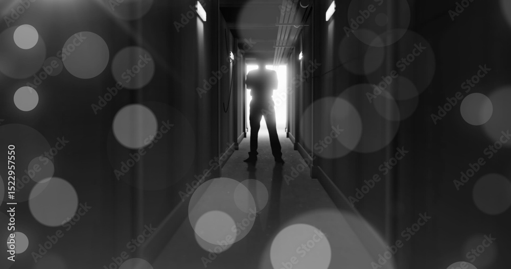 Fototapeta premium Image of grey bokeh light spots over scary figure backlit in doorway at end of dark corridor