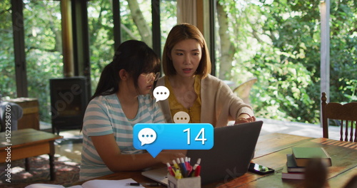 Image of social media icons with growing number over asian woman and her daughter using laptop