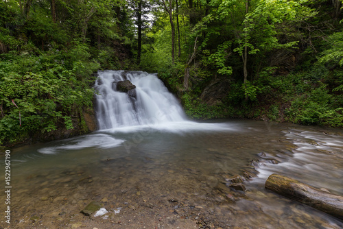 Waterfall in the mountains, river rapids, fast flow, Scenic view of pristine Carpathian nature with crystal clear water cascading over mossy rocks. Photo wallpaper, beauty of nature and the Earth.
