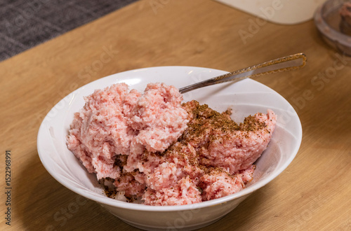 Just ground meat mince in the glass bawl of the electrical chopper on the kitchen counter top being seasoned and mixed. Cooking