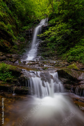 Waterfall in the mountains, river rapids, fast flow, Scenic view of pristine Carpathian nature with crystal clear water cascading over mossy rocks. Photo wallpaper, beauty of nature and the Earth.