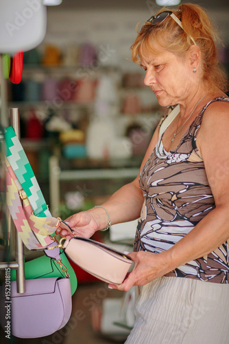 Mature woman chooses a handbag in the store. Shopping, fashion blog, sale, gift ideas concept