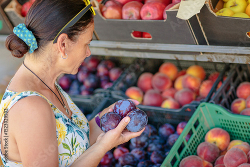 Mature woman choosing fruits in street shop in resort town. Summer healthy shopping in farm store