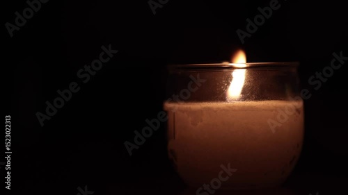 dettagli di una candela accesa che brucia nell'oscurità