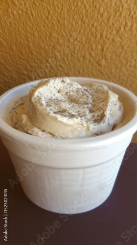 Delicious vanilla ice cream in a white paper cup with sprinkled poppy seeds for dessert