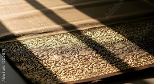Golden Textile With Intricate Pattern Bathed In Sunlight From Window