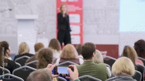 Blurred perspective of a presenter addressing a seated audience at an organized event